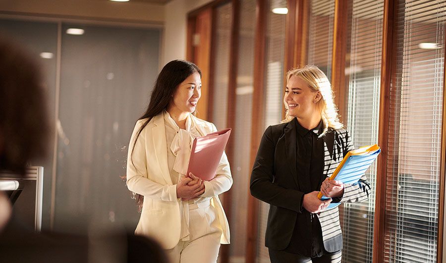 Two momen talking carrying files